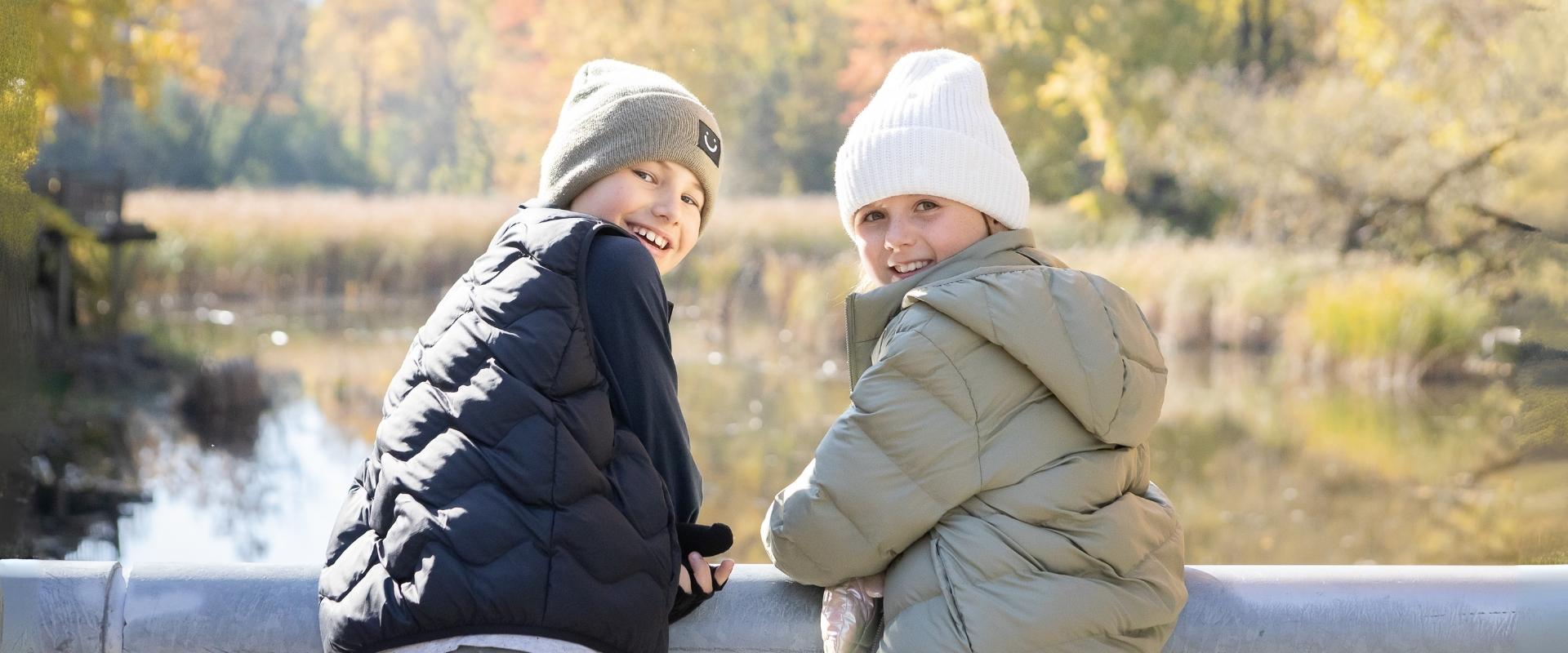 Kids in cozy fall jackets near a lake